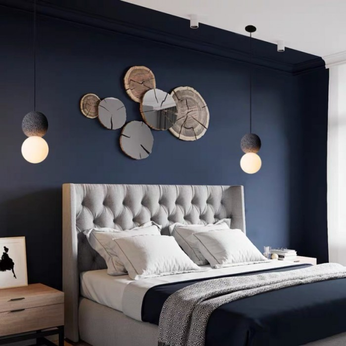 lifestyle two pendants flanking a wall art display above a navy bedroom headboard