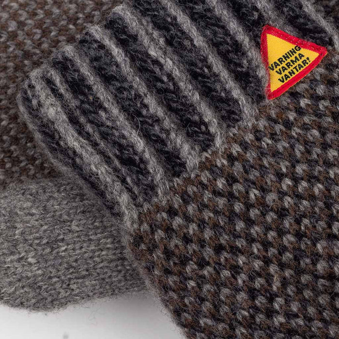 Textured gray and brown glove with a warning label on a textured surface